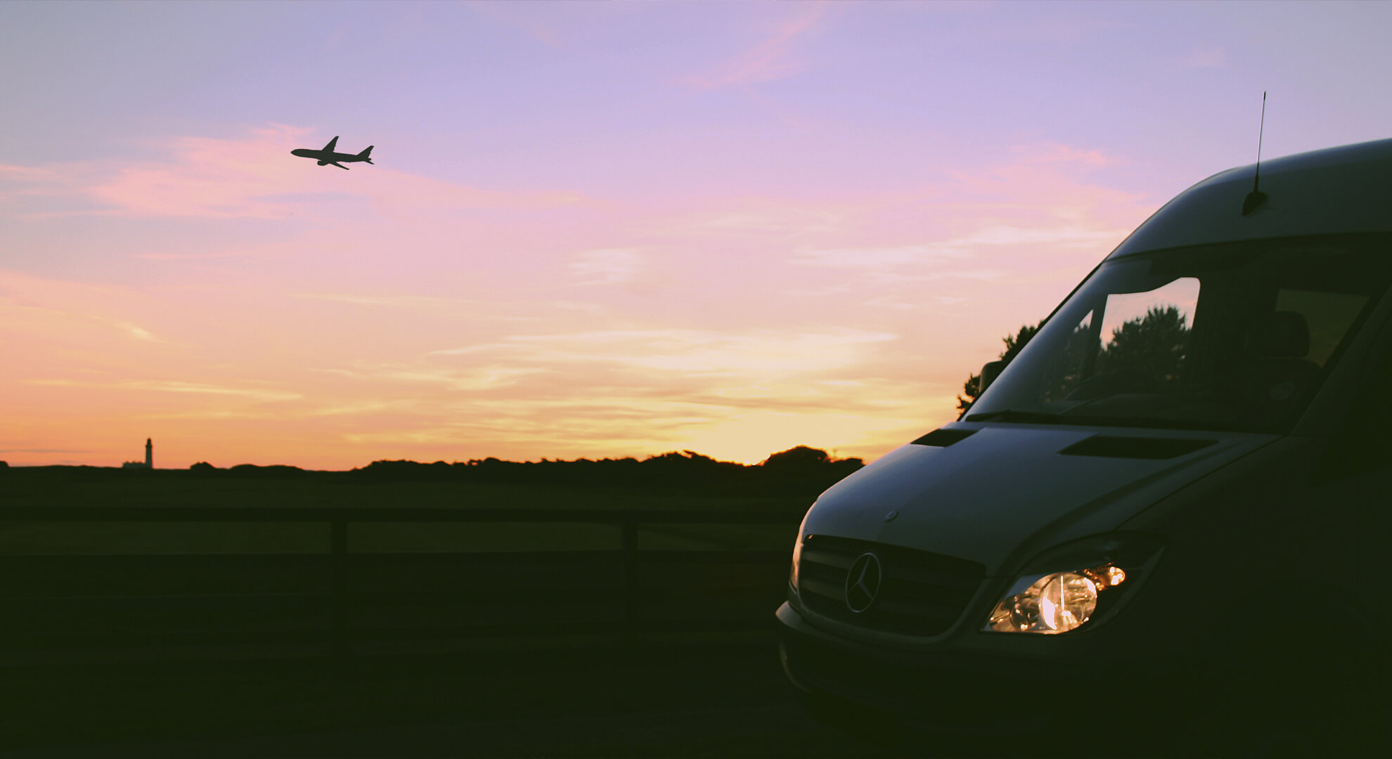 Night shot of minibus with plane in the distance